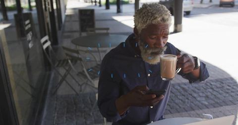 Sipping black man checking smartphone while enjoying latte at sidewalk cafe remote work