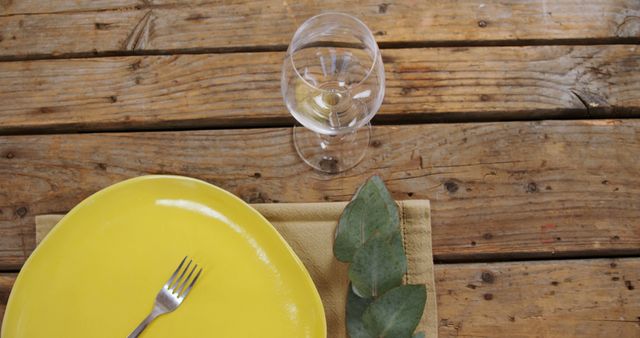 Empty yellow plate with wine glass on rustic wooden table outdoor - Download Free Stock Images Pikwizard.com