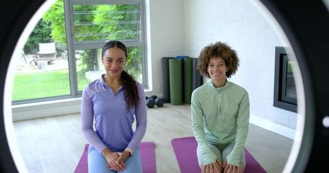 African american women practicing yoga together in bright home studio with ring light