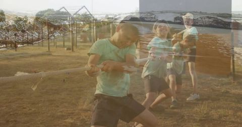 Boys engaged in energetic tug-of-war with scenic overlay