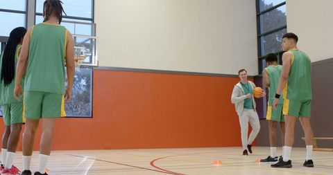 Basketball Coach Training Diverse Team on Gym Court