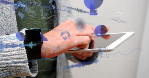 Male holding tablet tapping screen wearing smartwatch with data visualizations and charts