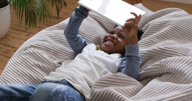 Happy Child Enjoying Tablet on Cozy Chair Indoors - Download Free Stock Images Pikwizard.com