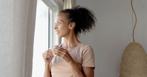 Woman savors morning coffee while gazing from window