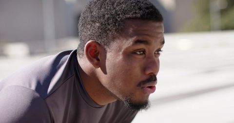 African American man catching breath after rooftop workout in bright sunlight