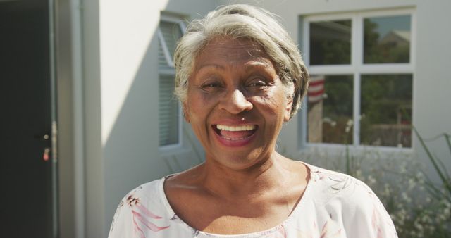 Senior woman smiling happily outdoors in natural light. Ideal for content related to senior living, happiness in elderly life, health and wellness, positive aging. Useful for promotional materials for retirement homes, healthcare services, and informal lifestyle articles.