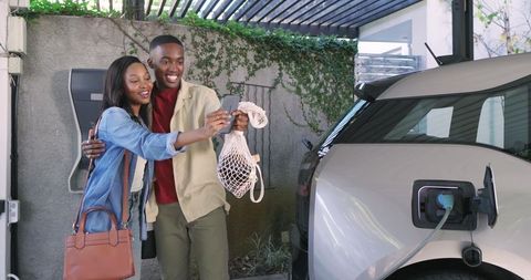 Young couple charging electric vehicle at home
