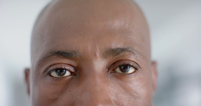 Professional setting highlighting an African American male doctor with a serious expression, captured in a close-up of his eyes. Useful for portraying professionalism in healthcare settings, representing focus and dedication in the medical field, or depicting diverse professionals in hospital infrastructure.