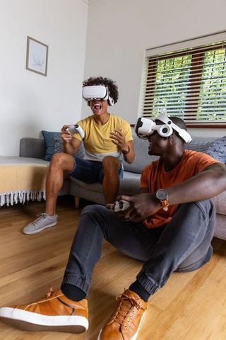 Friends enjoying wireless vr gaming session in bright modern living room with controllers