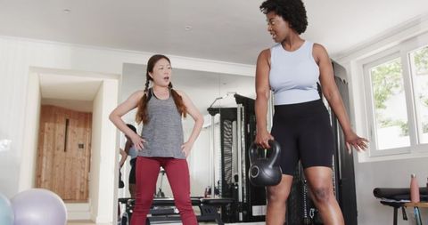 Personal trainer guiding kettlebell workout in home gym
