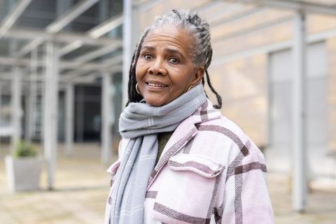 Senior african american woman smiling in urban plaza wearing plaid coat and gray scarf