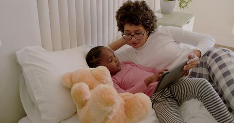 Mother and Daughter Relaxing on Bed Using Tablet Together