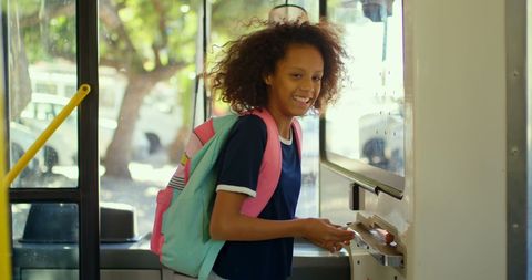 Cheerful girl buying bus ticket with backpack