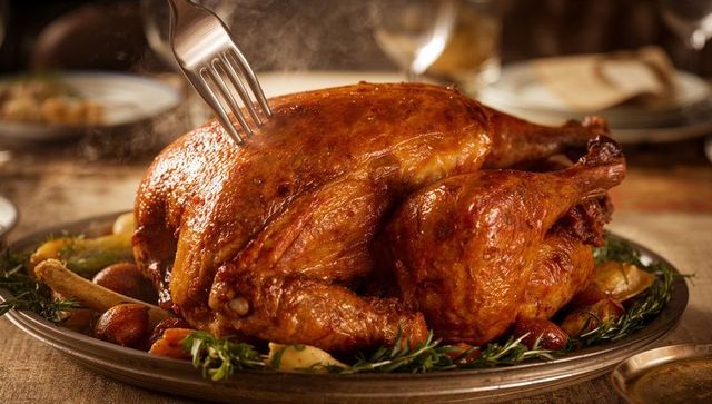 Golden roasted turkey steaming on platter with carving fork holiday feast centerpiece