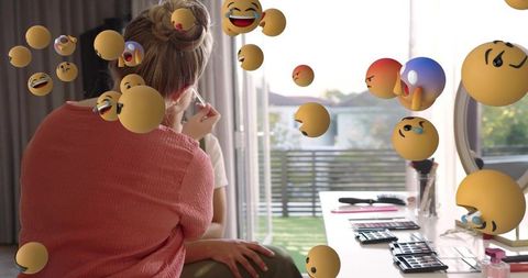 Applying bridal makeup at sunlit vanity with floating emoji overlays and beauty tools