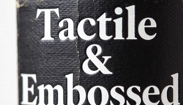 Close-up textured black label with embossed white serif typography and visible crease