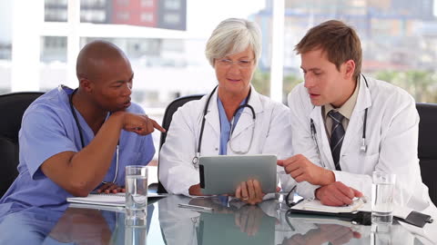 Doctors Collaborating in Bright Medical Office Using Tablet