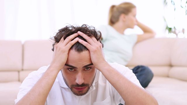 Young couple experiencing tension after an argument in their living room, both appearing distant and frustrated. Useful for articles about relationship issues, communication problems, mental health, and domestic conflict.