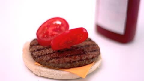 Slow Motion Tomatoes Falling on Burger with Cheese and Patty