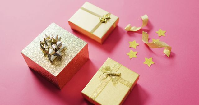 Image of wrapped gold presents and stars on pink background. christmas, tradition and celebration concept.
