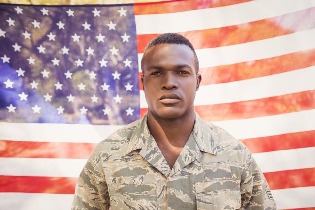 This image shows a soldier in uniform standing in front of an American flag. It can be used for themes related to patriotism, military service, national pride, and Veterans Day. Ideal for use in articles, advertisements, and social media posts honoring military personnel.