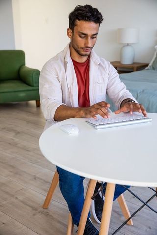 Man typing at home workspace in contemporary bedroom setting