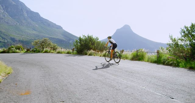 Cyclist on mountain road during sunny day with picturesque views - Download Free Stock Images Pikwizard.com