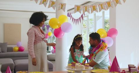 Family Celebrating Child's Birthday with Balloons and Cake at Home