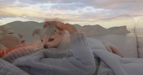 Child cradling small dog on couch during coastal sunset double exposure serene cozy pastel