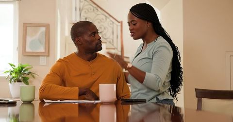 Couple Discussing Paperwork at Home with Coffee in Morning