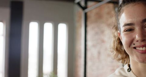 Young Woman Smiling in Industrial-Style Studio with Brick Walls