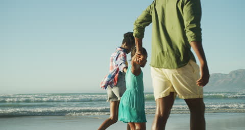 Happy Family Enjoying Walk Along Sandy Beach