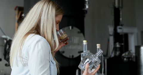 Young woman evaluating aroma of distilled spirit in glass