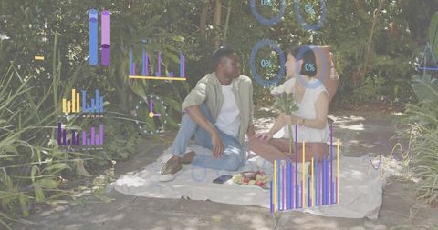 Couple sitting on picnic blanket sharing bouquet with digital data overlays in garden