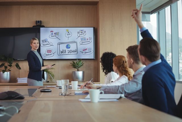 Businesswoman presenting web design ideas to her team in a modern office conference room. Ideal for use in articles or advertisements related to business meetings, corporate presentations, teamwork, and professional collaboration.