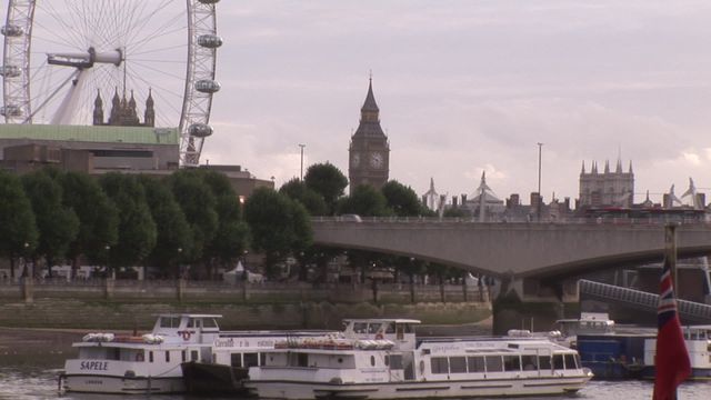 London's iconic landmarks such as the London Eye and Big Ben with a view of the River Thames on an overcast day. Highlights the unique blend of historical and modern architecture with boats docked along the river. Ideal for travel blogs, tourism advertisements, or educational content showcasing famous London sights.