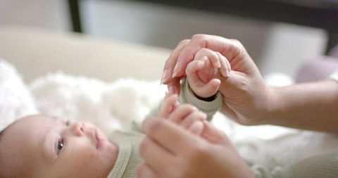 Mother Joyfully Interacting with Newborn in Cozy Nursery Setting