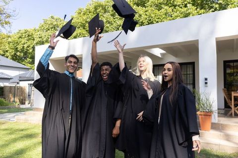 Diverse Graduates Celebrating Outdoors In Academic Gowns