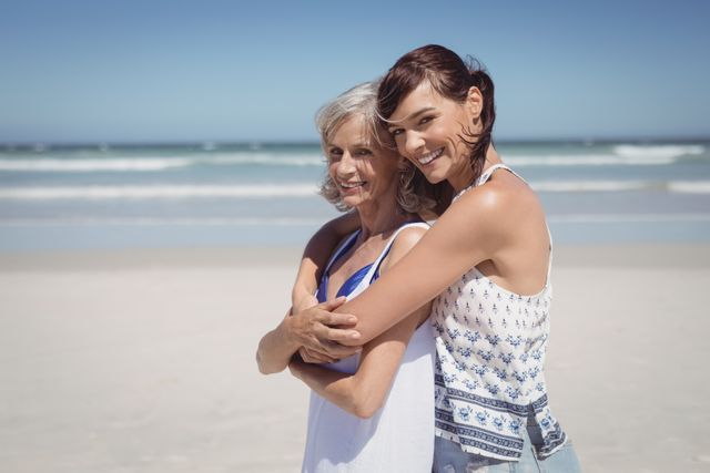 This image shows a joyful moment between a woman and her mother at the beach on a sunny day. Perfect for use in family-oriented advertisements, travel brochures, or articles about family relationships and bonding. It can also be used in promotions for beach vacations, summer activities, and outdoor lifestyle content.