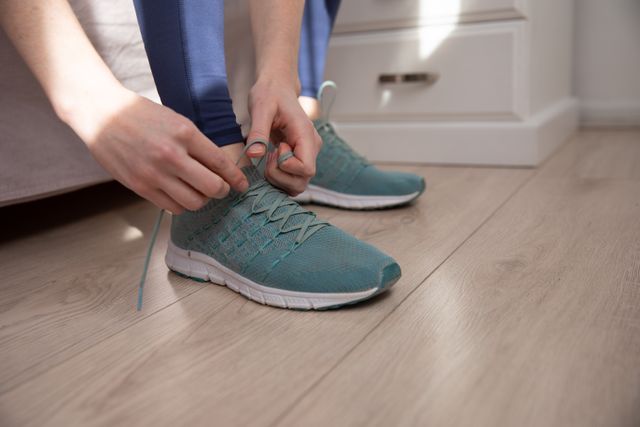 Mid section of woman tying her shoelaces at home - Download Free Stock Photos Pikwizard.com