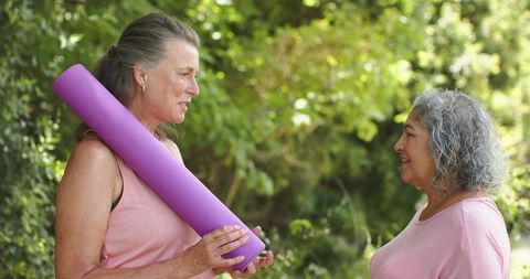 Two Senior Women Conversing with Yoga Mat in Nature