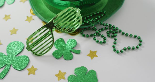 Brightly colored accessories lying on a white surface include green shamrocks, novelty glasses, and a hat, creating a festive mood. Great for St. Patrick's Day greeting cards, holiday event promotions, or social media posts.