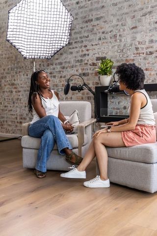 African american women recording candid podcast interview in urban studio with softbox lighting
