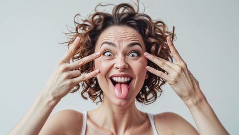 Playful woman with curly hair making a crazy funny face
