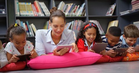 Teacher and Kids Using Tablets Lying on Library Floor - Download Free Stock Images Pikwizard.com
