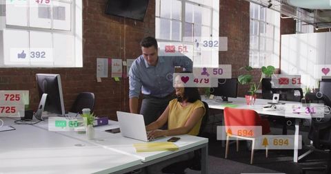 Collaborating in modern loft office with laptop, social media notifications and teamwork