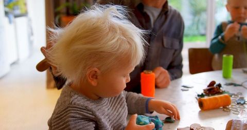 Father Combing Daughter's Hair as She Plays at Home