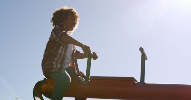 Child enjoying a moment on a seesaw in an outdoor playground. Perfect for themes related to childhood joy, playful activities, outdoor fun, and carefree moments.