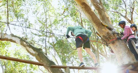 Group Navigating High Ropes Course in Forest with Helmets