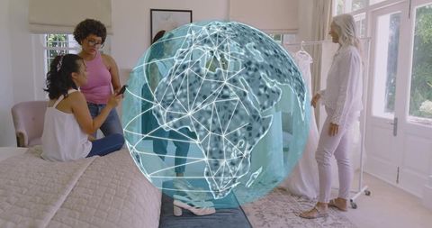 Women collaborating on wardrobe styling at home with futuristic holographic globe connection